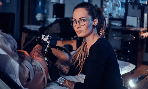 beautiful-creative-master-with-dreadlocks-is-working-new-peace-big-leg-tattoo-customer_613910-2929